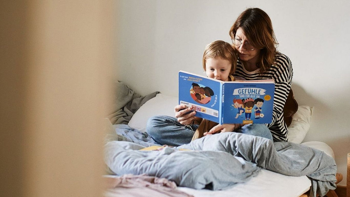 Mutter liest ihrem Kind im Bett gemütlich ein Buch vor.