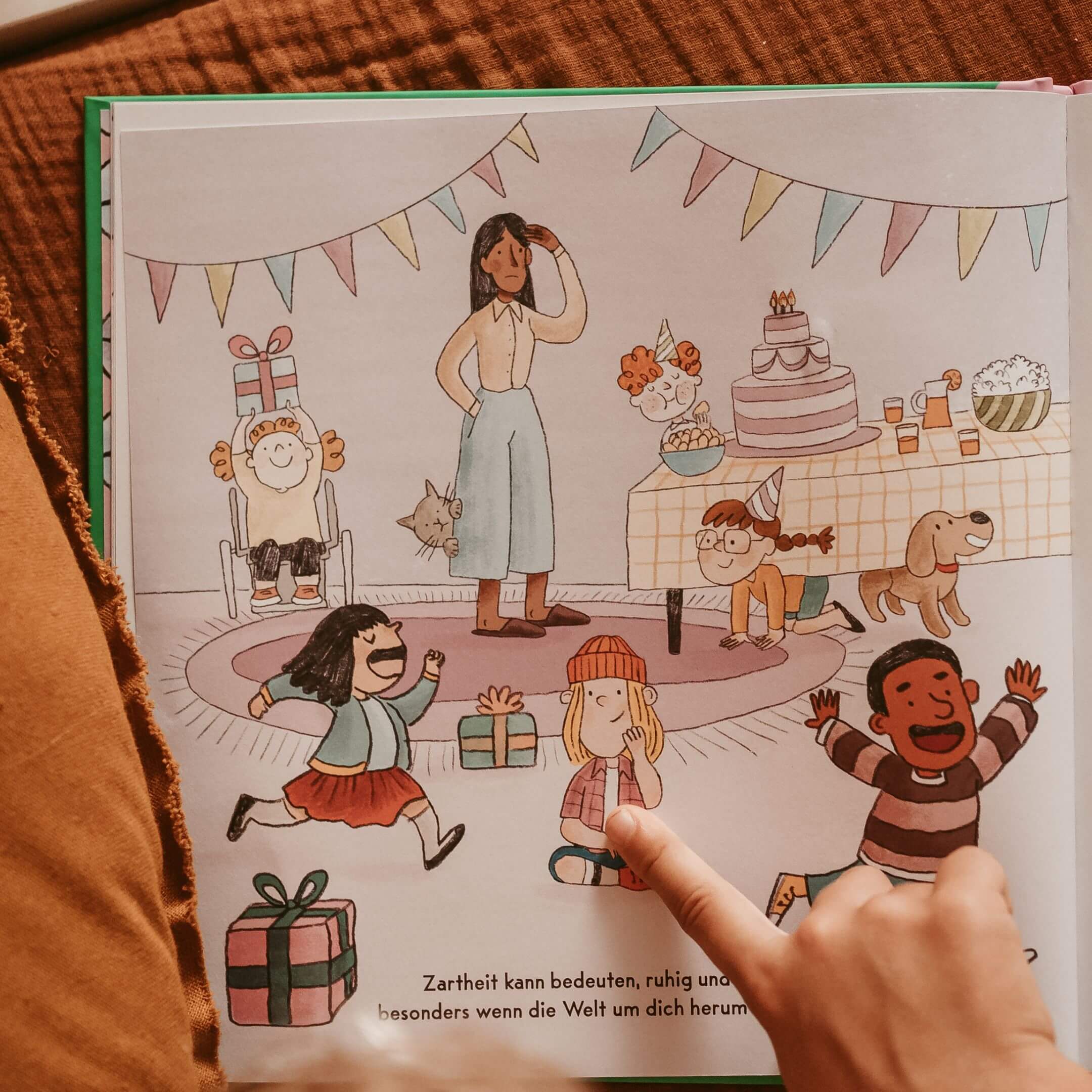 Bei einer Geburtstagsfeier spielen Kinder mit Luftballons und Kuchen, während eine lächelnde Frau zusieht. Ein Kind im Rollstuhl nimmt freudig am Spiel teil.