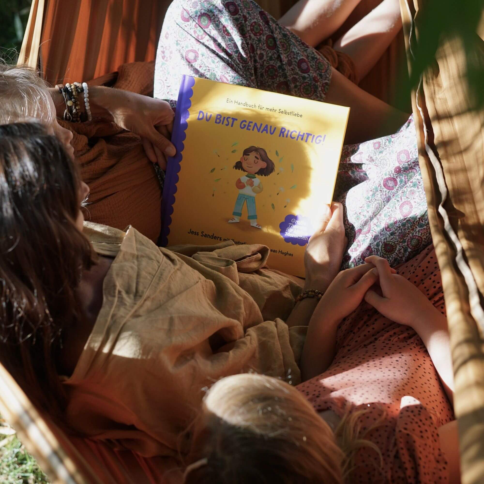 Drei Menschen entspannen sich gemeinsam in einer Hängematte und lesen