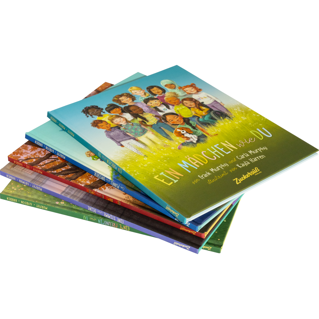 Ein Stapel bunter Kinderbücher des Zuckersüß Verlags mit der Aufschrift "Eine Welt wie diese - Mädchen-Kollektion" zeigt auf einem weißen Umschlag illustrierte Mädchen unterschiedlicher Herkunft.