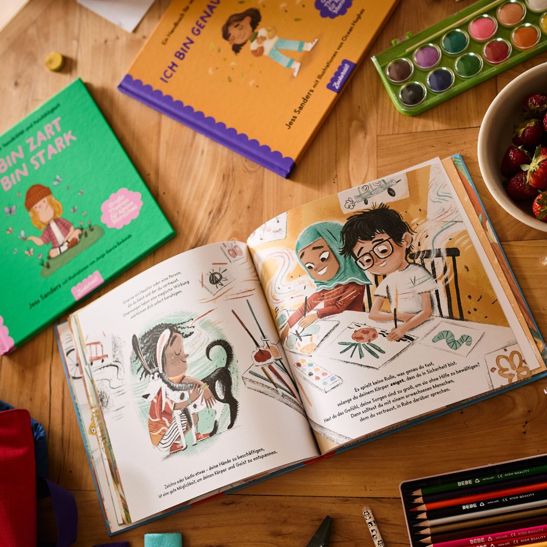 Das Schulstarter-Paket des Zuckersüß Verlags enthält illustrierte deutsche Kinderbücher, Wasserfarben, Buntstifte, Malutensilien und eine Schale Erdbeeren – ideal für Aktivitäten zum Schulstart, die das Selbstvertrauen der Kinder stärken.