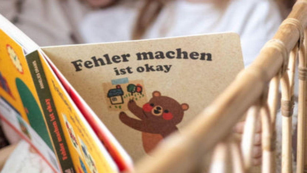 Ein Kind hält ein Buch mit dem Titel ,,Fehler machen ist okay''