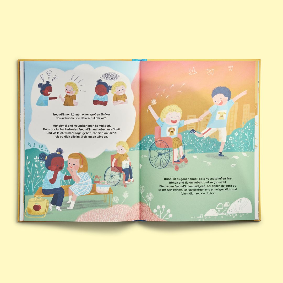 Eine Doppelseite aus dem Buch „Das allerbeste Schuljahr“ vom Zuckersüß Verlag zeigt verschiedene Kinder, darunter eines im Rollstuhl, die ihren Schultag im Freien genießen. Einige sitzen auf einer Picknickdecke, während andere herumlaufen und sich unterhalten, dargestellt durch ausdrucksstarke Sprechblasen.
