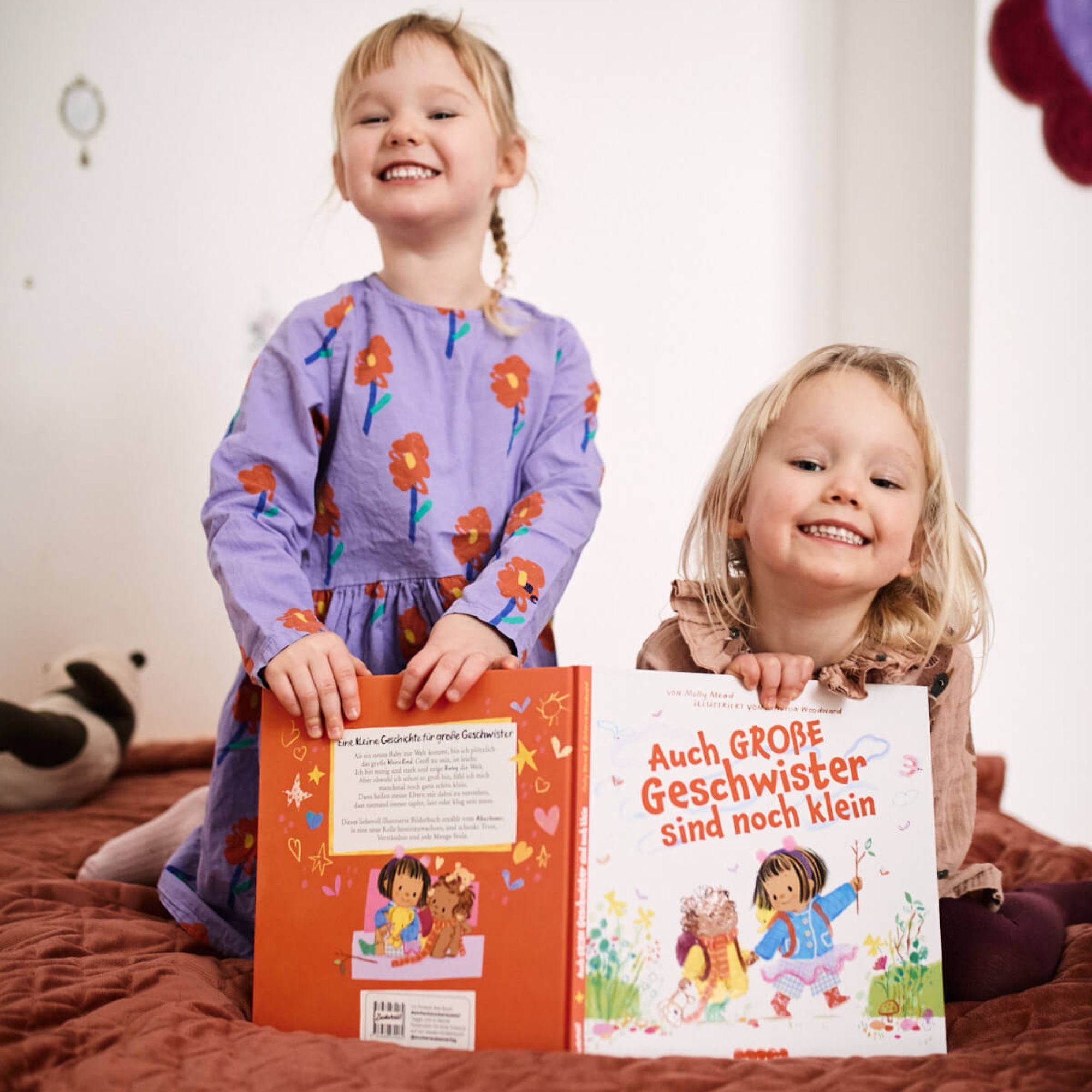 Zwei Kinder lächeln und halten das Buch 